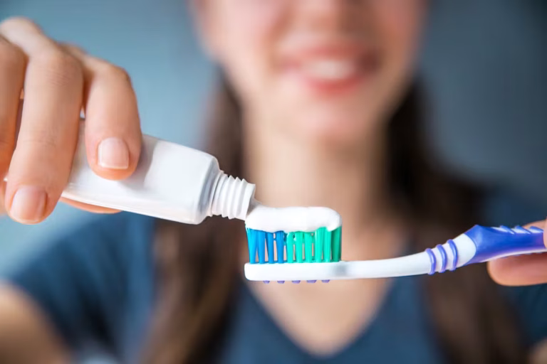 femme qui met du dentifrice sur sa brosse à dent