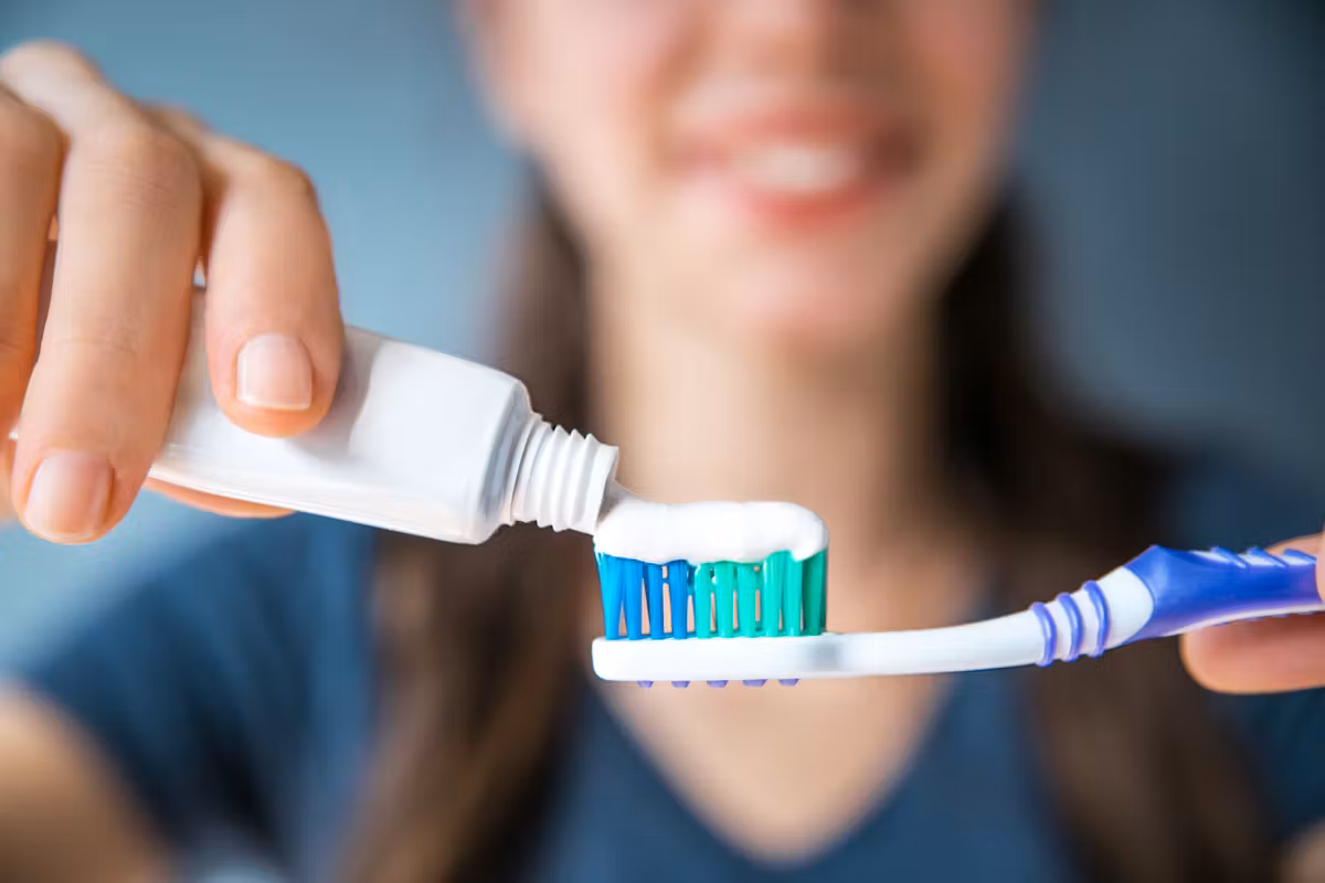 femme qui met du dentifrice sur sa brosse à dent
