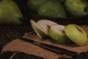Bienfaits de la poire fruit entier coupé sur planche bois