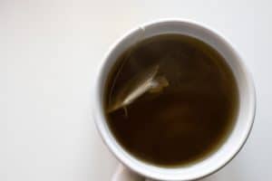 Tisane rhume au thym miel et citron dans une tasse fumante sur table en bois