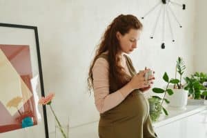 Femme enceinte buvant du rooibos enceinte en cuisine lumineuse